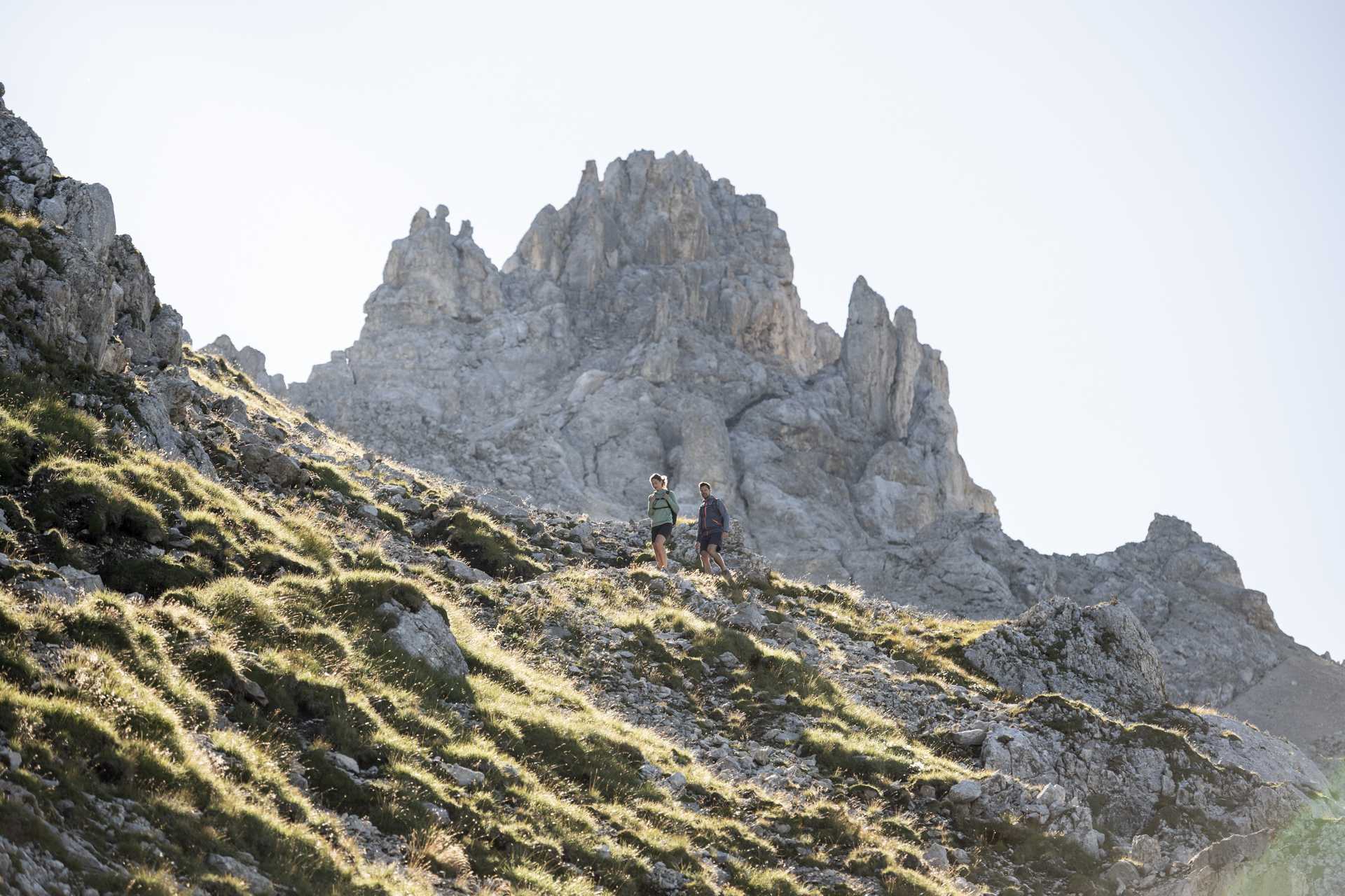The climb can sometimes be difficult, but you are rewarded with a stunning view. Two people on a mountain hike. A large mountain peak is visible in the background.