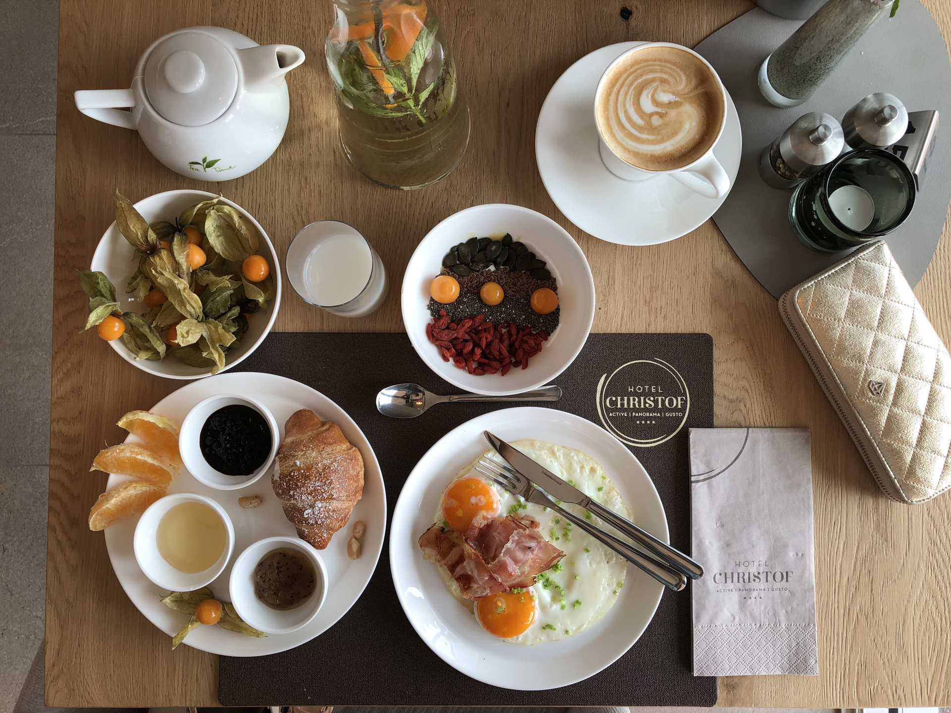 Tavolo della colazione con uova, croissant, frutta, cereali, marmellata, caffè e tè
